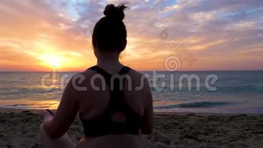 坐在沙滩上练习瑜伽的女人剪影